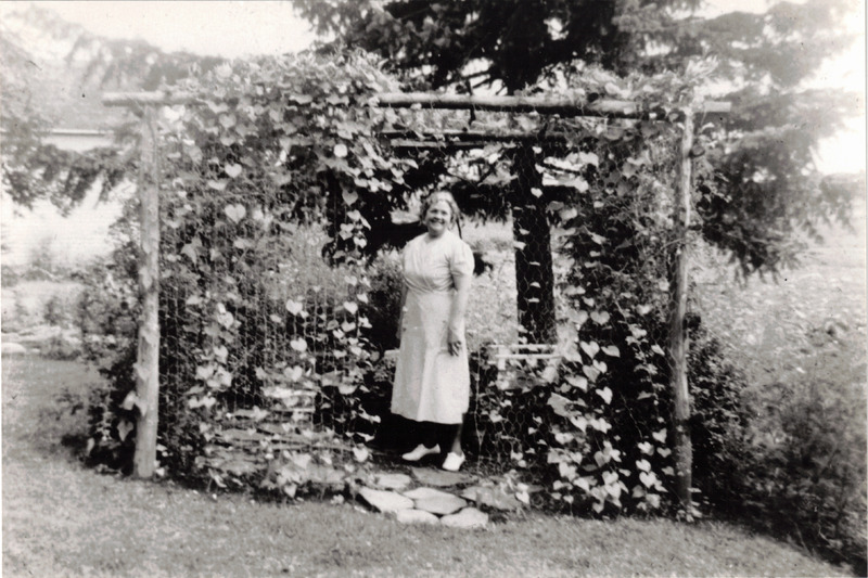 Photo of Anna Haushalter in a backyard arbor c. 1950s