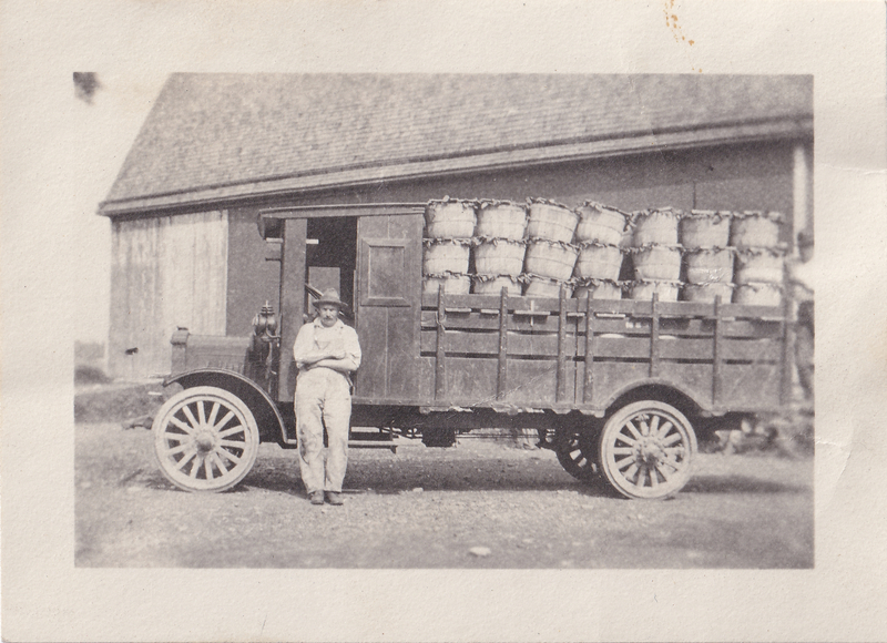 Charles Haushalter leans against a Service Motor Truck loaded with produce, c. 1920